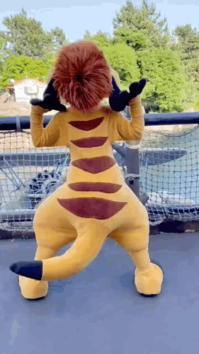 A Stuffed Animal In A Lion Costume Is Standing In Front Of A Net GIF