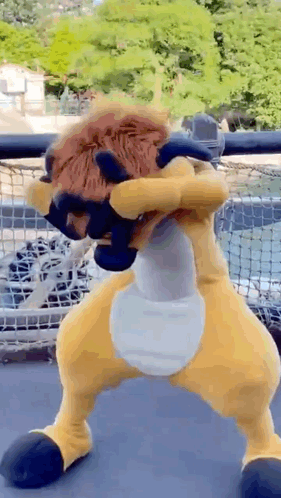 A Stuffed Animal In A Lion Costume Is Standing On A Balcony . GIF