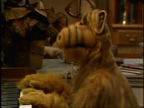 A Stuffed Animal Is Playing A Piano With Its Mouth Open GIF