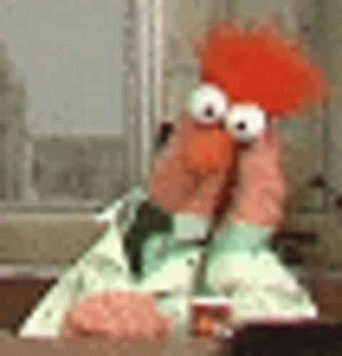A Stuffed Animal Is Sitting At A Table Holding A Stuffed Animal In Its Hands . GIF