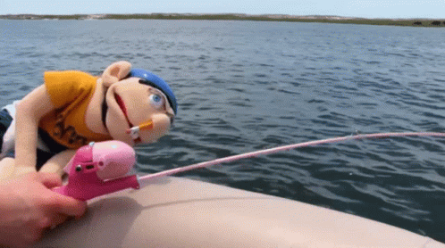 A Stuffed Animal On A Boat With A Fishing Rod And A Cigarette In Its Mouth GIF