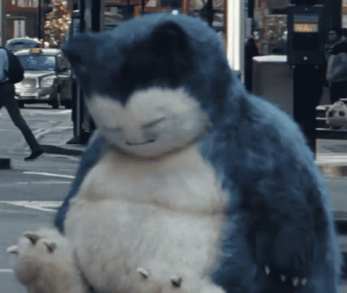 A Stuffed Animal That Looks Like Snorlax Is Sitting On The Sidewalk GIF