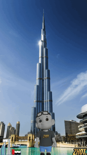 A Stuffed Animal Wearing A Shirt That Says Zhot Stands In Front Of A Dubai Skyscraper GIF