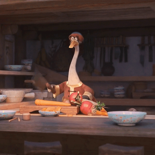 A Stuffed Animal With A Long Neck Is Sitting On A Counter With Vegetables GIF