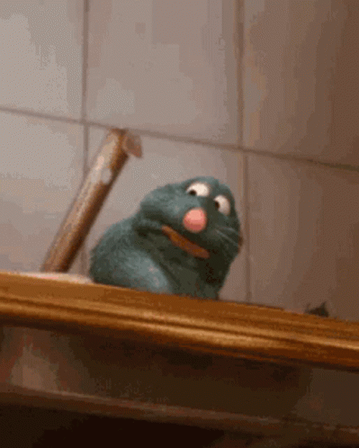 A Stuffed Animal With A Pink Nose Is Sitting On A Wooden Shelf . GIF