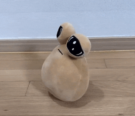 A Stuffed Animal With Big Eyes Is Sitting On A Hardwood Floor GIF