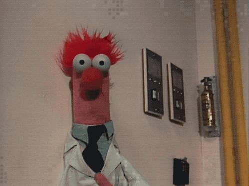 A Stuffed Animal With Red Hair Is Wearing A Lab Coat And A Tie GIF