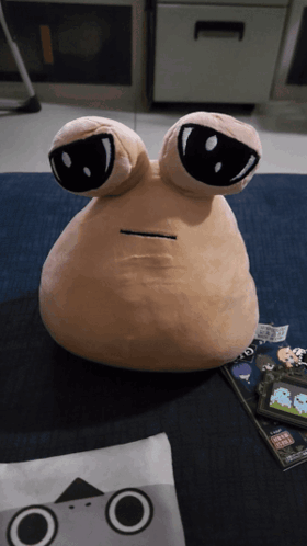 A Stuffed Animal With Two Eyes Is Sitting On A Carpet GIF