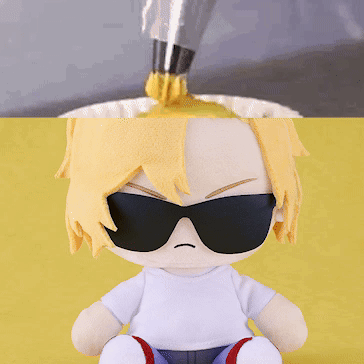 a stuffed doll wearing sunglasses is sitting on a yellow table