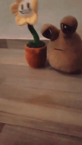 A Stuffed Flower And A Stuffed Snail Are On A Wooden Floor GIF