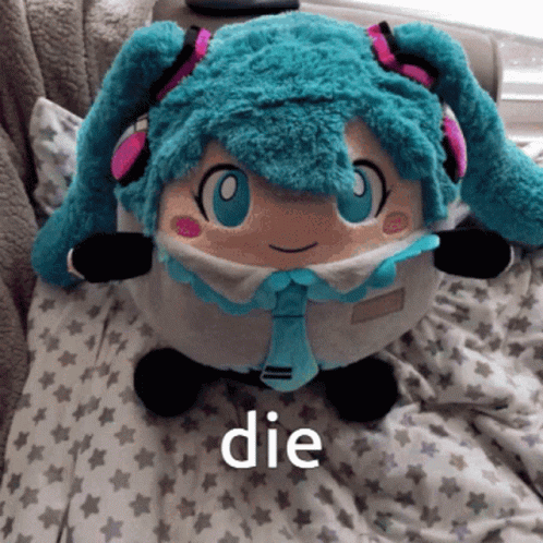 A Stuffed Hatsune Miku Doll Is Laying On A Bed With The Word Die Below It GIF