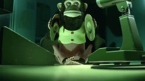 A Stuffed Monkey Is Sitting In Front Of A Camera In A Dark Room GIF