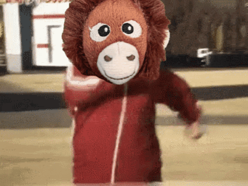 A Stuffed Monkey Wearing A Red Jacket And A Mask GIF