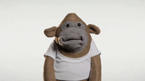 A Stuffed Monkey Wearing A White Shirt Is Making A Surprised Face GIF