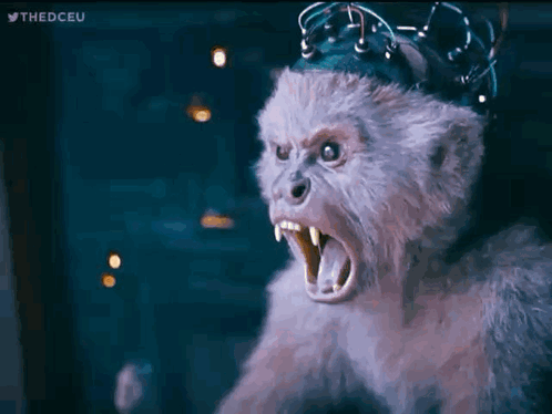 A Stuffed Monkey With A Crown On Its Head Is Looking At The Camera With Its Mouth Open . GIF