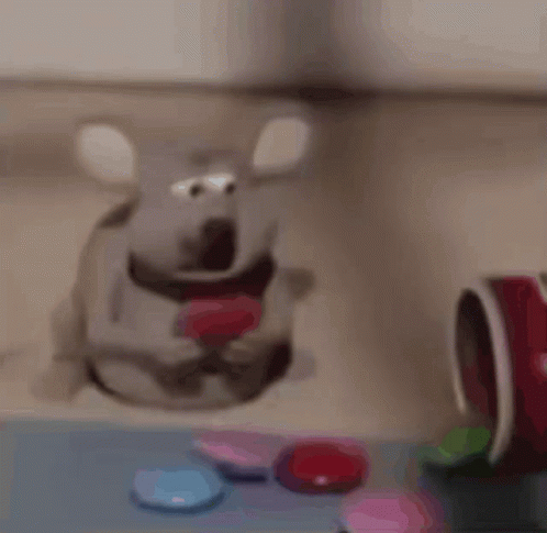 A Stuffed Mouse With A Heart In Its Mouth Is Sitting On A Table With Candy . GIF