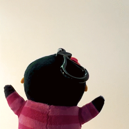 A Stuffed Penguin Wearing A Pink And Black Striped Sweater With A Keychain Attached To It GIF