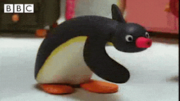 A Stuffed Penguin With A Pink Nose Is Standing On A White Surface . GIF
