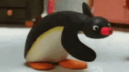 A Stuffed Penguin With A Pink Nose Is Standing On A White Surface . GIF