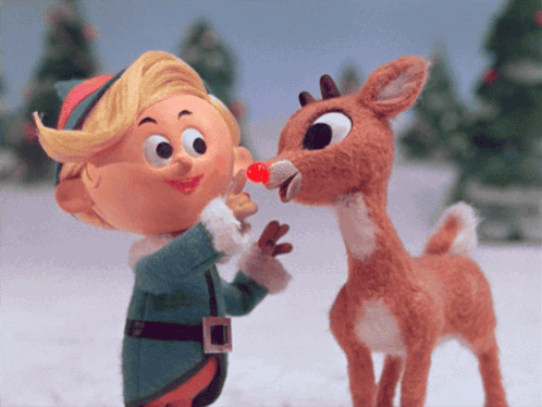 A Stuffed Reindeer With A Red Nose Is Being Kissed By A Little Elf GIF