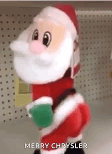 A Stuffed Santa Claus Is Standing In Front Of A Shelf And Holding A Christmas Ball . GIF