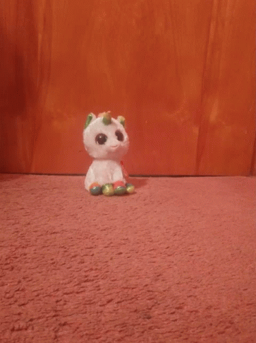 A Stuffed Unicorn With A Rainbow Horn Is Looking At The Camera GIF