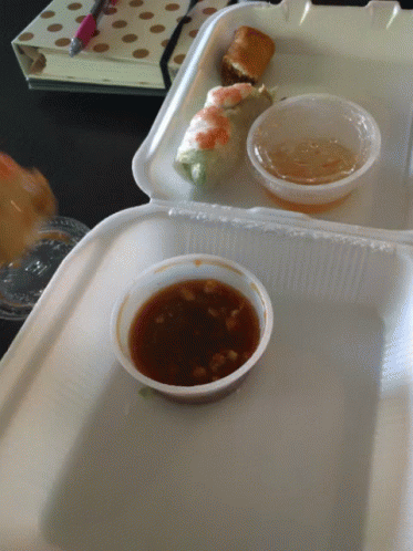 A Styrofoam Container Filled With Food And Dipping Sauces GIF