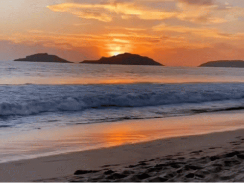 A Sunset Over A Beach With A Few Islands In The Distance GIF