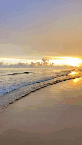A Sunset Over A Beach With Waves Crashing On The Sand GIF