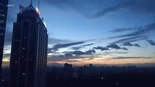 A Sunset Over A City With A Skyscraper In The Foreground That Says ' Jakarta ' On It GIF
