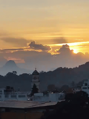 A Sunset Over A City With A Tower In The Foreground GIF