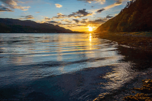 A Sunset Over A Lake With Mountains In The Background And A Watermark That Says ' Ocbu Drinkhoe ' GIF