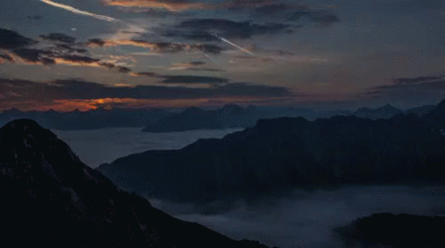A Sunset Over A Mountain Range With A Few Clouds In The Sky GIF