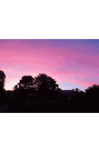 a sunset over a parking lot with a brick building in the background