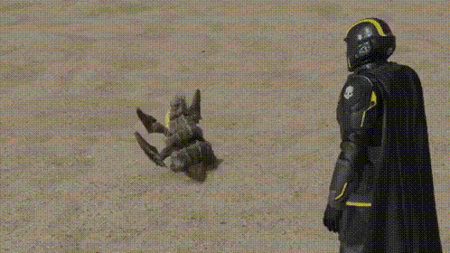 A Superhero In A Black Cape And Helmet Is Standing Next To A Toy Robot . GIF