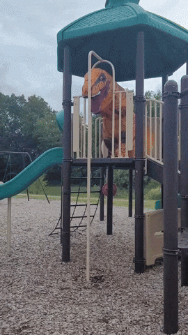 A T-Rex Costume Is On A Playground Set GIF