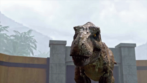 A T-Rex Is Standing In Front Of A Stone Wall GIF