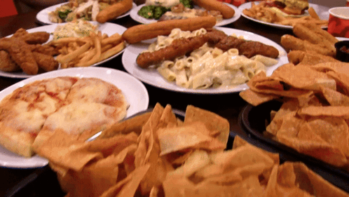A Table Full Of Plates Of Food Including A Pizza GIF