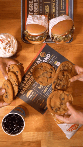 A Table Topped With Hamburgers And Cookies With A Sign That Says The Last Great Hamburger GIF