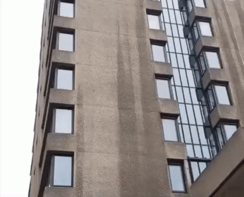 A Tall Building With Lots Of Windows And A White Sky In The Background GIF