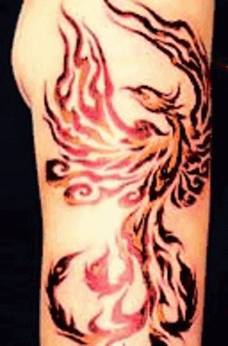 A Tattoo Of A Phoenix On A Person 'S Arm . GIF