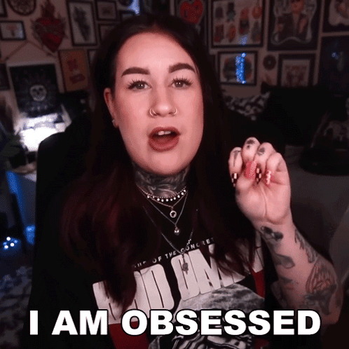 A Tattooed Woman Says I Am Obsessed In Front Of A Wall Of Pictures GIF