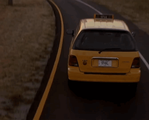 A Taxi Is Driving Down A Road With A City In The Background GIF