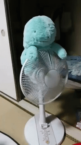 A Teal Stuffed Animal Is Sitting On Top Of A White Fan GIF