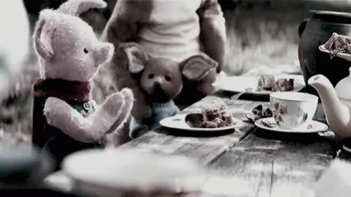 A Teddy Bear And A Pig Are Sitting At A Table With Plates Of Food . GIF
