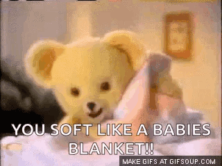 A Teddy Bear Is Laying On A Bed With The Words You Soft Like A Babies Blanket GIF