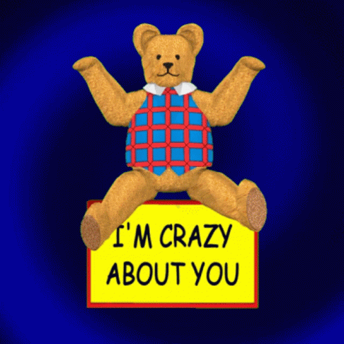A Teddy Bear Is Sitting On A Yellow Sign That Says I 'M Crazy About You GIF