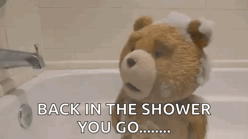 A Teddy Bear Is Taking A Bath In A Bathtub With Foam On It . GIF