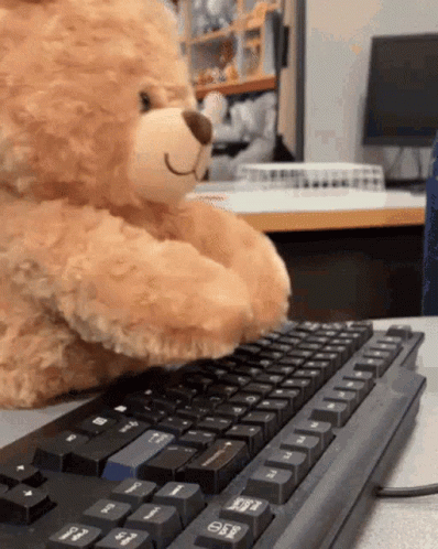 a teddy bear is typing on a black keyboard with the esc key visible