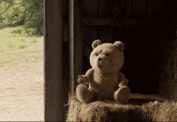 A Teddy Bear Sits In A Pile Of Hay GIF
